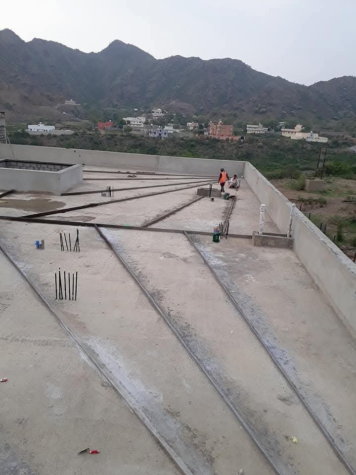 عامل بناء يملأ فراغات جدار خرساني باستخدام الخرسانة الرغوية في موقع بناء